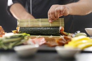 sushi master twisting sushi nori rolls on a bamboo mat