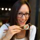 Smiling woman eating sushi with chopsticks in Japanese restaurant