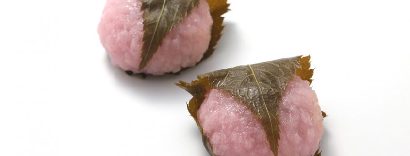 Sakuramochi, japanese confectionery wrapped in a preserved cherry on white background.