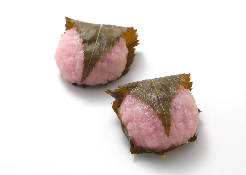 Sakuramochi, japanese confectionery wrapped in a preserved cherry on white background.