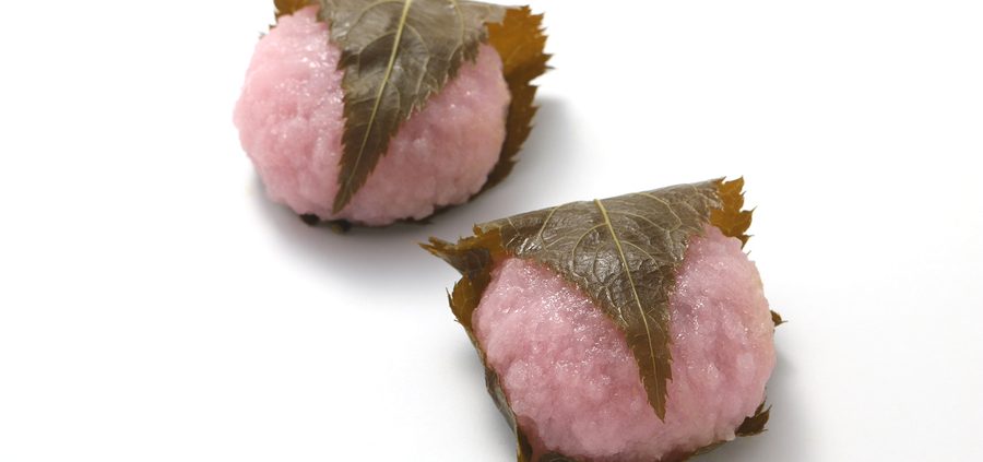 Sakuramochi, japanese confectionery wrapped in a preserved cherry on white background.
