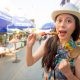 young girl traveler enjoying delicious grilled yakitori chicken skewers on street market in Japan