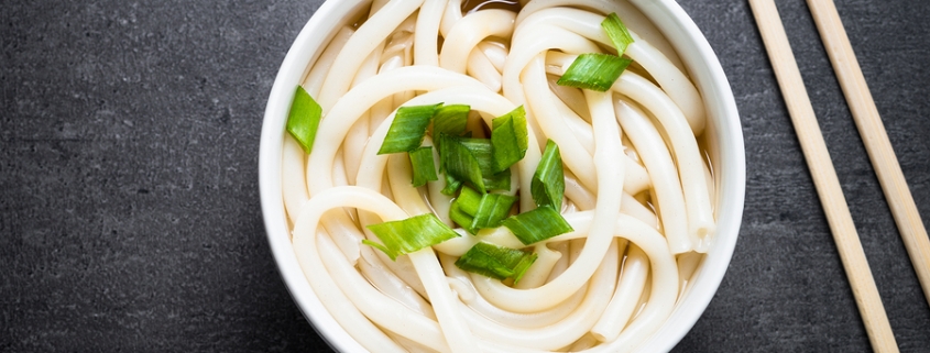 Udon Japanese noodles in a bowl on black slate table. Traditional Japanese dish.